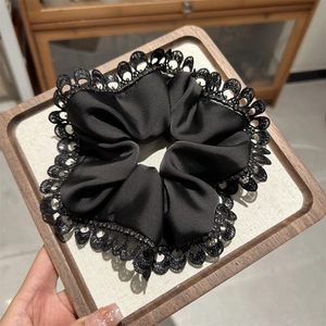 Detail of elegant black satin hair scrunchie with lace edge and subtle glitter details