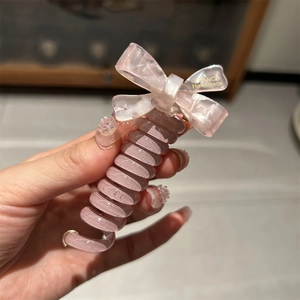 Close-up of pink spiral hair tie with France Handmade bow detail and glossy resin texture