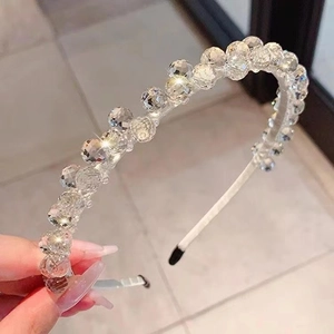 Nahaufnahme glitzernder Kristallperlen auf einem schmalen weißen Haarreif für Damen