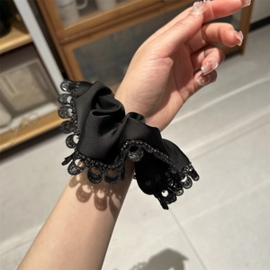 Detail of a black lace scrunchie with satin fabric and sparkling rhinestone accents