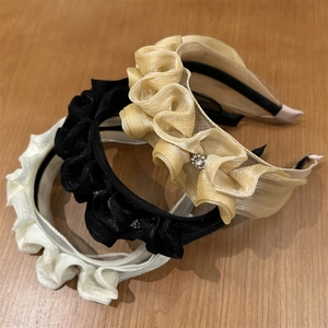 Detailed texture of ruffled organza headbands in beige, black, and champagne gold