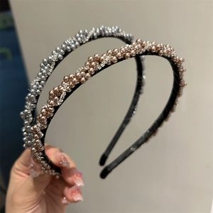 Détail de bandeaux tressés en perles avec strass en argent et champagne tenus à la main