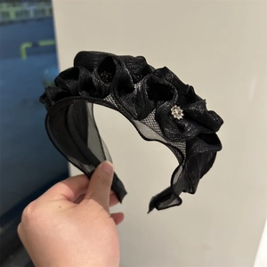 Detail of black organza ruffled headband with sparkling rhinestone flower embellishment