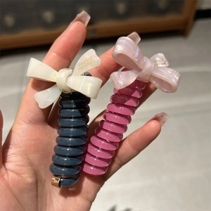 Detail of spiral hair ties with acetate bows in grey-blue and pink colors
