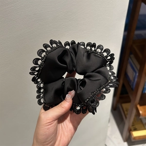 Close-up of elegant black lace scrunchie with satin fabric and high elasticity