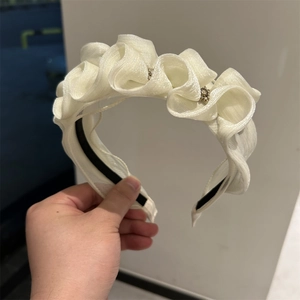 Detail of cream organza headband featuring pleated fabric and sparkling rhinestone accents