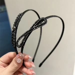 Détail de serre-têtes noirs élégants avec nœud en strass et motifs de vagues