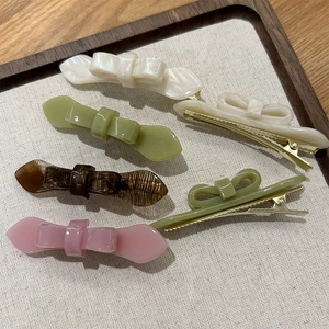 Detail of five acetic acid bow hair clips with gold metal grips in various colors