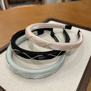 Close-up of three braided satin headbands with metallic chains in a display tray
