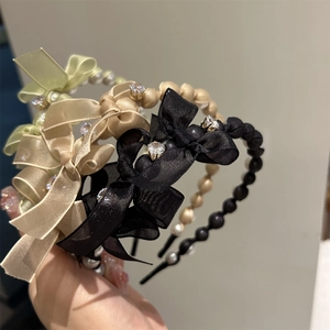 Detail of silk bow headband with faux pearls and rhinestones in champagne and black