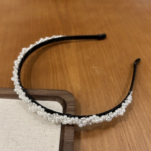Détail de l'étroit serre-tête noir orné de perles blanches nacrées et de petits strass brillants