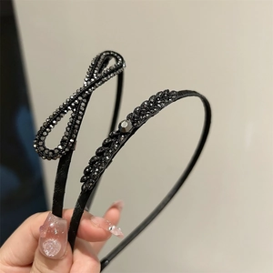 Détail de nœuds et feuilles en strass noirs sur des serre-têtes fins et élégants
