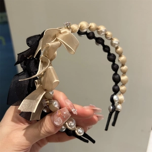 Detail of pearl headband with silk ribbon bow showing elegant craftsmanship and texture