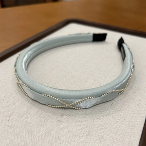Close-up of light blue satin headband with elegant gold bead chain braiding