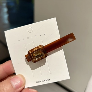 Detail of amber brown acetate hair clip with square yellow crystal and tortoise pattern