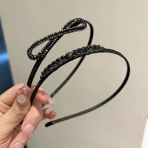 Détail du nœud en strass noir et motif feuille sur un serre-tête fin en métal noir