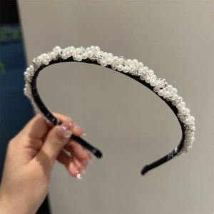 Détail d'un serre-tête tressé élégant avec perles blanches et strass brillants