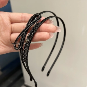 Détail de deux serre-têtes noirs fins ornés de nœuds en strass et motifs géométriques