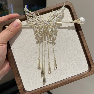 Dettaglio di un fermaglio per capelli a farfalla dorata con zirconi, nappe e perle