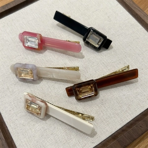 Macro shot of five assorted acetate hair clips with crystal inlay on linen display