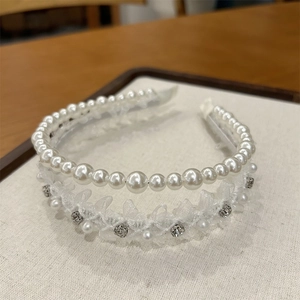 Détail d'un serre-tête blanc double épaisseur avec dentelle perles et strass sur fond beige