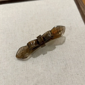 Detail of tortoiseshell acetate bow hair clip with textured wings on linen tray