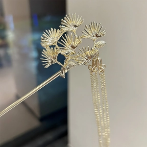 Close-up of golden pine branch hair pin with elegant metallic fringe tassels