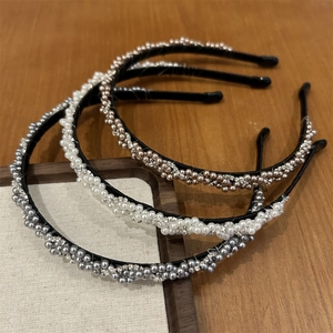 Détail de serre-têtes tressés avec perles et strass sur un fond en bois sombre