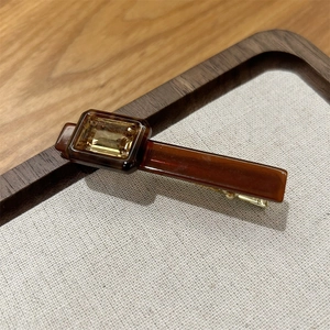 Macro detail of amber acetate hair clip with square rhinestone and gold metal grip