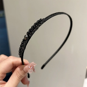 Détail du serre-tête en cuir noir orné d'embellissements en strass sombres en forme de feuille