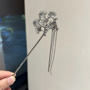 Detailed shot of pine needle metal hair stick with flowing silver tassels in sunlight