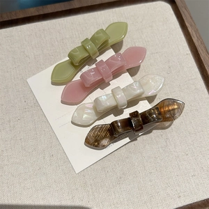 Detail view of 4-piece acetate butterfly hair clips in green, pink, white, and amber colors