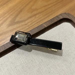 Close-up of black acetate hair clip with amber crystal and gold metal base