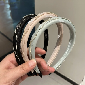 Close-up of padded satin headbands with golden bead chain wrap in black, pink, and green