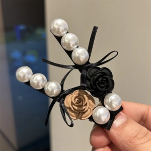 Detailed view of hair clips with camellia flower accents and white pearls in elegant style