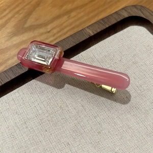 Macro detail of pink acetate hair clip with sparkling rhinestone on gold metal base