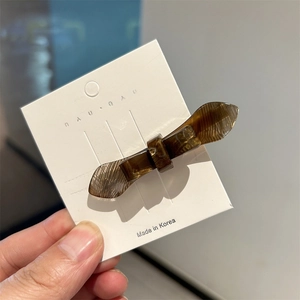 Minimalist double-layered amber acetate bow hair clip on a white display card
