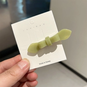 Minimalist light green acetate bow hair clip with polished finish on display card