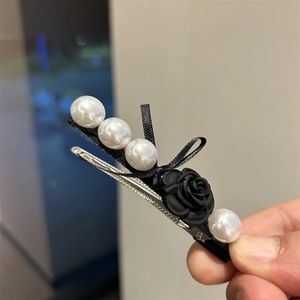 Detail of vintage hair clip with white pearls, black ribbon bow and matte rose flower
