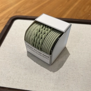 Detail of light green braided hair bands with high elasticity in a neat branded box