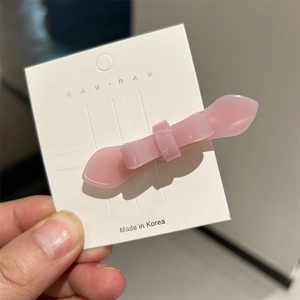 Close-up of a pink acetate double-layered bow hair clip on a white display card