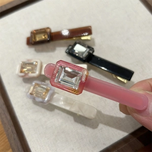Detailed close-up of colorful acetate hair clips with emerald-cut sparkling crystals