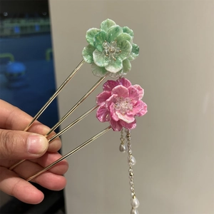 Détail d'épingles à cheveux fleurs en résine faites main avec de longs pompons dorés