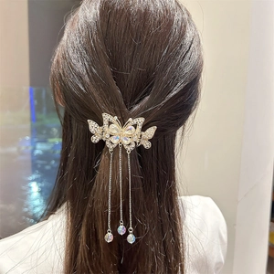 Détail d'une pince à cheveux papillon dorée avec strass blancs et longues franges