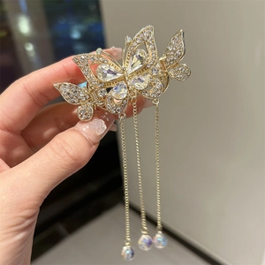 Détail de la pince à cheveux papillon dorée avec strass et longues chaînes à glands