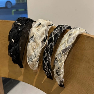 Dettaglio di cerchietti in maglia intrecciata con ciondoli a stella e catene in metallo