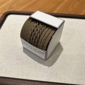 Close-up of coffee brown braided high elasticity hair bands in minimalist white packaging
