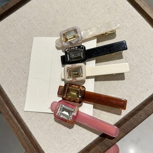 Detailed top view of five acetate hair clips with rectangular crystals in various colors