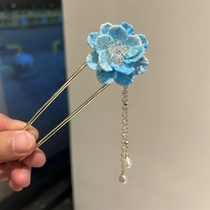 Détail de l'épingle à cheveux fleur bleue avec franges dorées et perles blanches