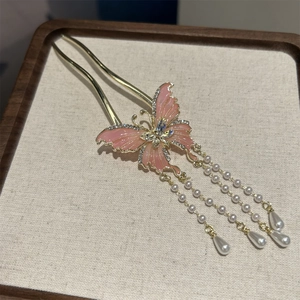 Detail of golden butterfly hair pin with pink enamel wings and pearl tassels